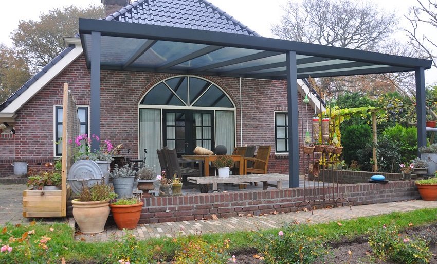 L'entrée de la maison est décorée d'un large auvent en feuilles de polycarbonate L'entrée de la maison est décorée d'un large auvent en feuilles de polycarbonate