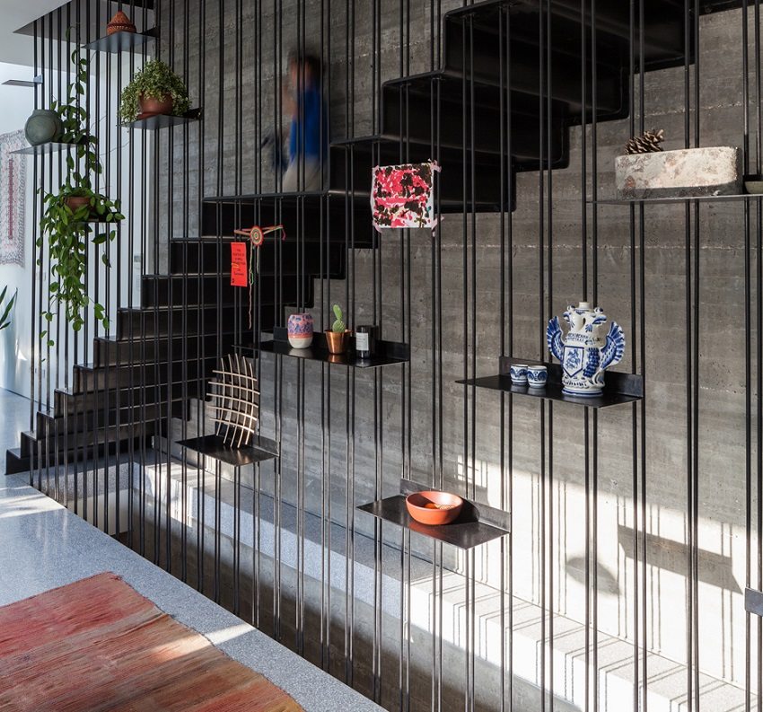 Стенно метално стълбище е оградено с декоративна завеса от метална щанга с рафтове за декор Стенно метално стълбище е оградено с декоративна завеса от метална щанга с рафтове за декор