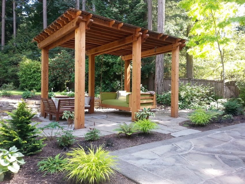 Un gazebo en bois avec un banc de balançoire équipé Un gazebo en bois avec un banc de balançoire équipé