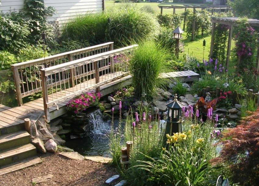 W ogrodzie znajduje się staw i drewniany mostek nad nim W ogrodzie znajduje się staw i drewniany mostek nad nim