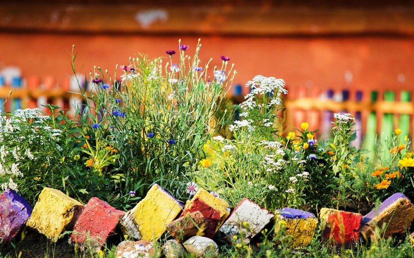 Mursten, malet i forskellige farver, blev brugt som blomsterbedhegn Mursten, malet i forskellige farver, blev brugt som blomsterbedhegn