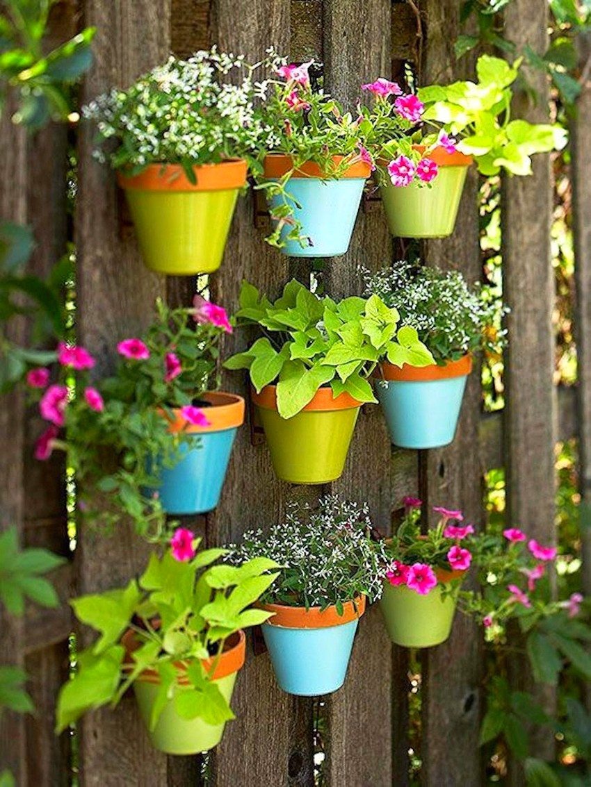 Et lodret blomsterbed med farverige potter dekorerer en træhæk Et lodret blomsterbed med farverige potter dekorerer en træhæk