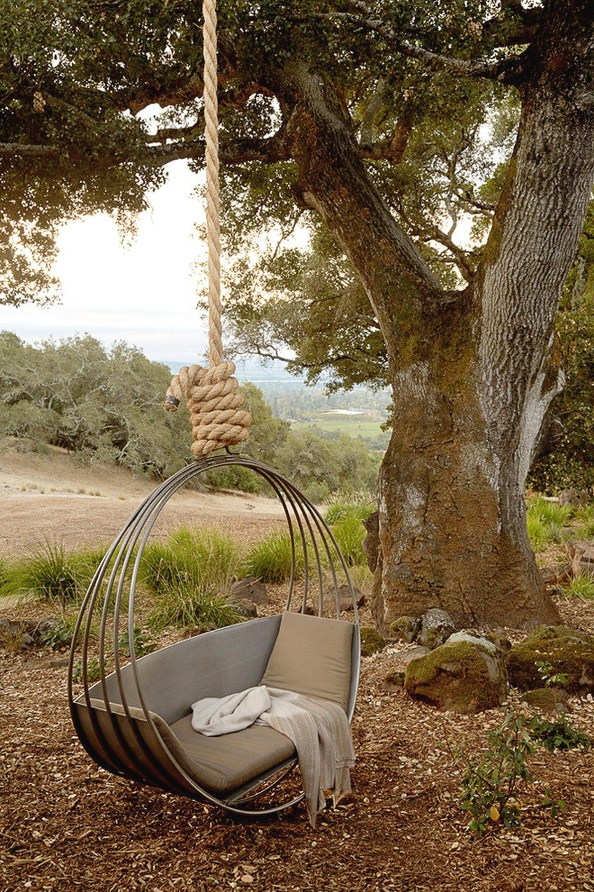 Alkuperäisen muotoinen metallikääntö ripustettuna puun oksalle köydellä Alkuperäisen muotoinen metallikääntö ripustettuna puun oksalle köydellä