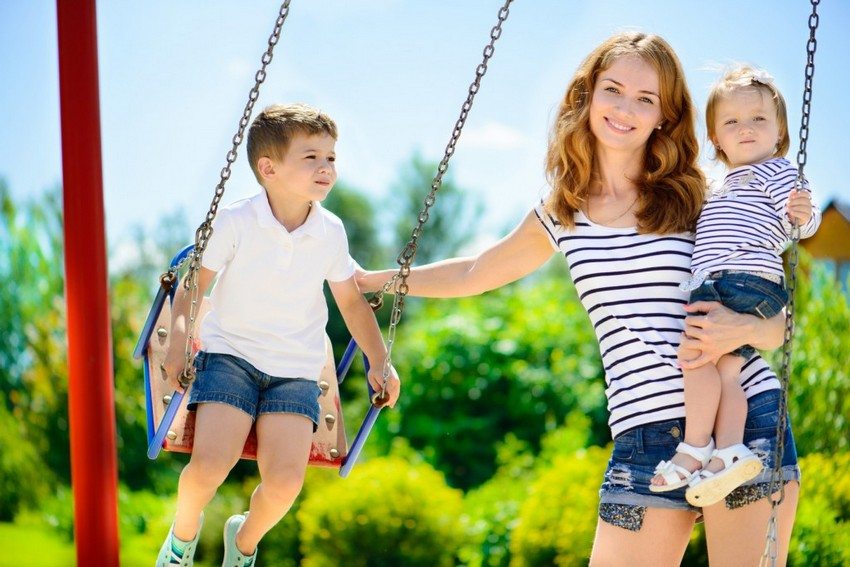 Ang swing ng mga bata na may metal frame, pininturahan ng maliliwanag na kulay Ang swing ng mga bata na may metal frame, pininturahan ng maliliwanag na kulay