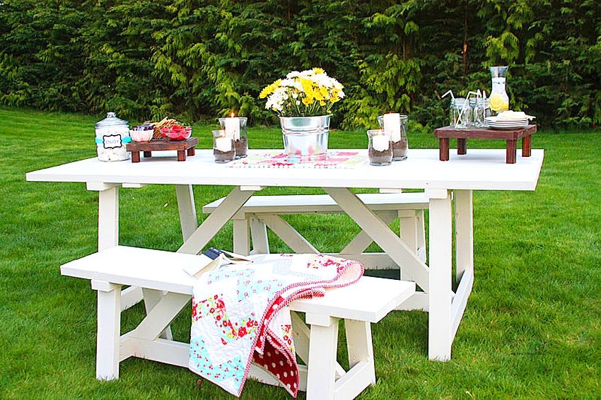 White painted wooden table and benches create a cozy dining area in the garden White painted wooden table and benches create a cozy dining area in the garden