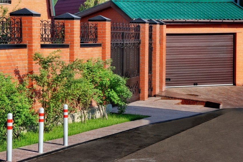 Brick bakod na may mga elemento ng forging sa paligid ng isang bahay sa bansa Brick bakod na may mga elemento ng forging sa paligid ng isang bahay sa bansa