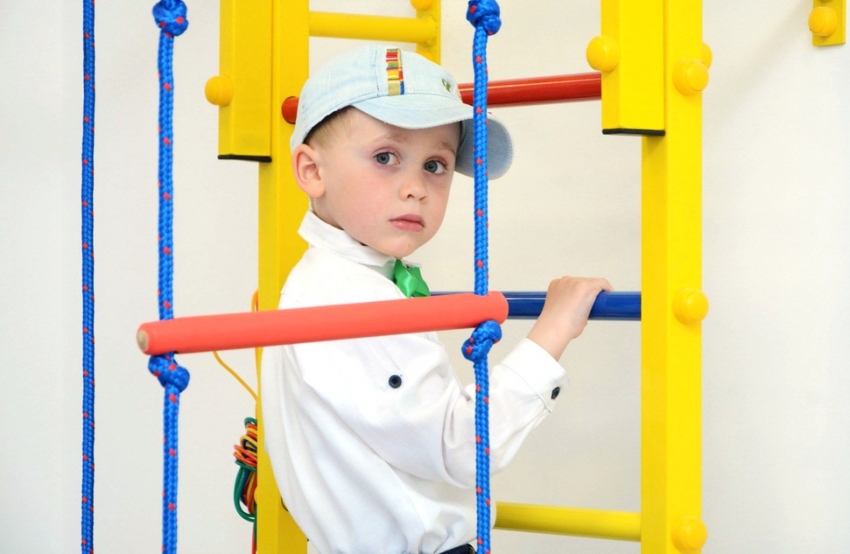 Els esports d’un nen a la paret sueca només s’han de fer amb el suport i la presència d’un adult Els esports d’un nen a la paret sueca només s’han de fer amb el suport i la presència d’un adult