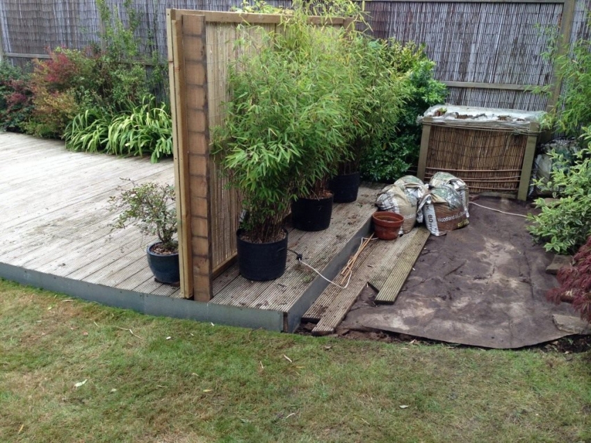 Eksempel på maskering av en kompostbeholder med et lite gjerde og planter Eksempel på maskering av en kompostbeholder med et lite gjerde og planter