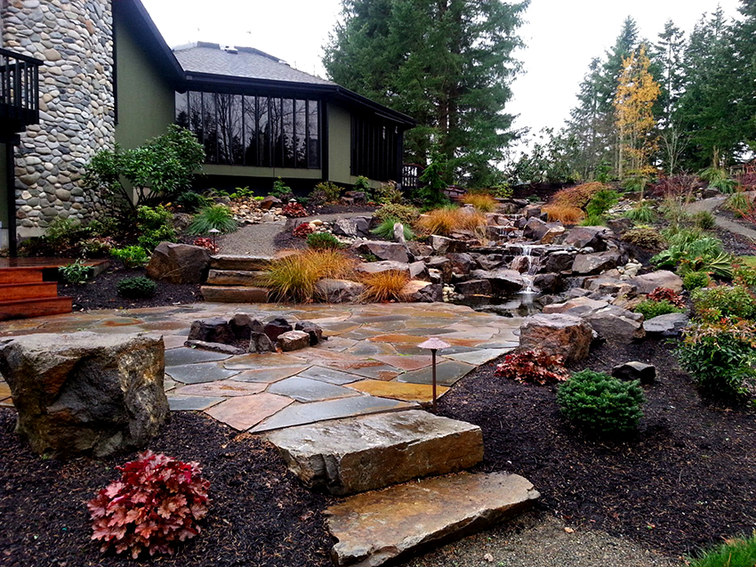 A virágok és kövek többszintű elrendezésével ellátott alpesi csúszda a tájtervezés kiemelt részévé válik A virágok és kövek többszintű elrendezésével ellátott alpesi csúszda a tájtervezés kiemelt részévé válik