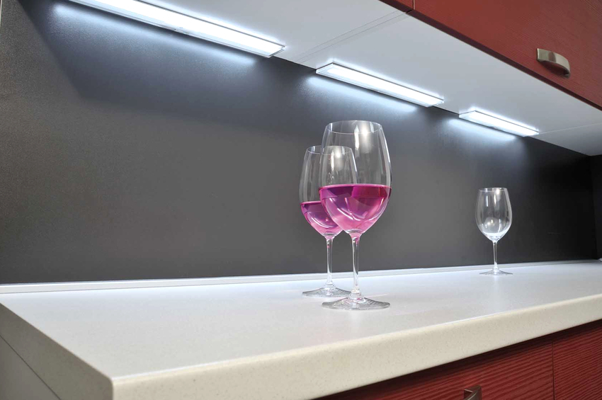 Lineær belysning på kjøkkenet under skapene er organisert ved hjelp av lamper som ligger ved siden av hverandre på kort avstand Lineær belysning på kjøkkenet under skapene er organisert ved hjelp av lamper som ligger nær hverandre på kort avstand