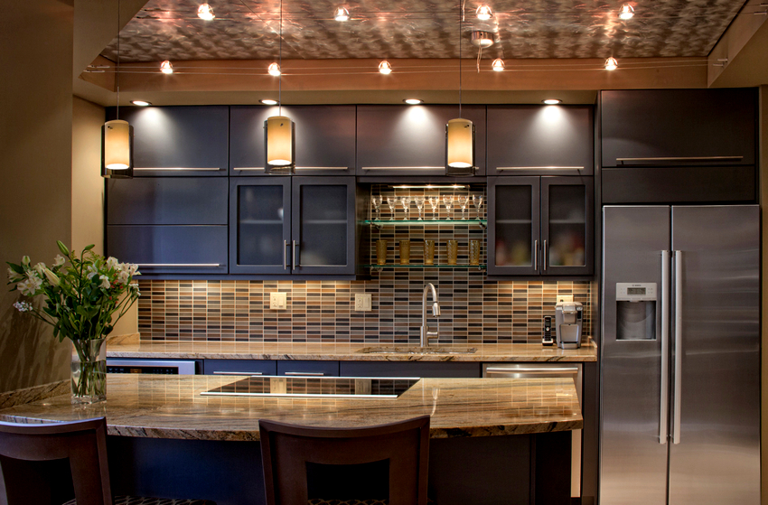 Hvis lampene er plassert langs linjen til kjøkkenenheten i taket, vil det være mulig å gi belysning av en smal del av bordplaten. Hvis lampene er plassert langs linjen til kjøkkenet i taket, vil det være mulig å gi belysning av en smal del av benkeplaten.